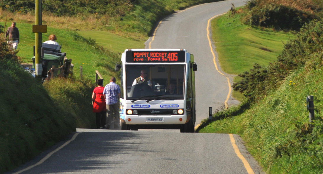 Bus picking up passengers on a narrow coastal road