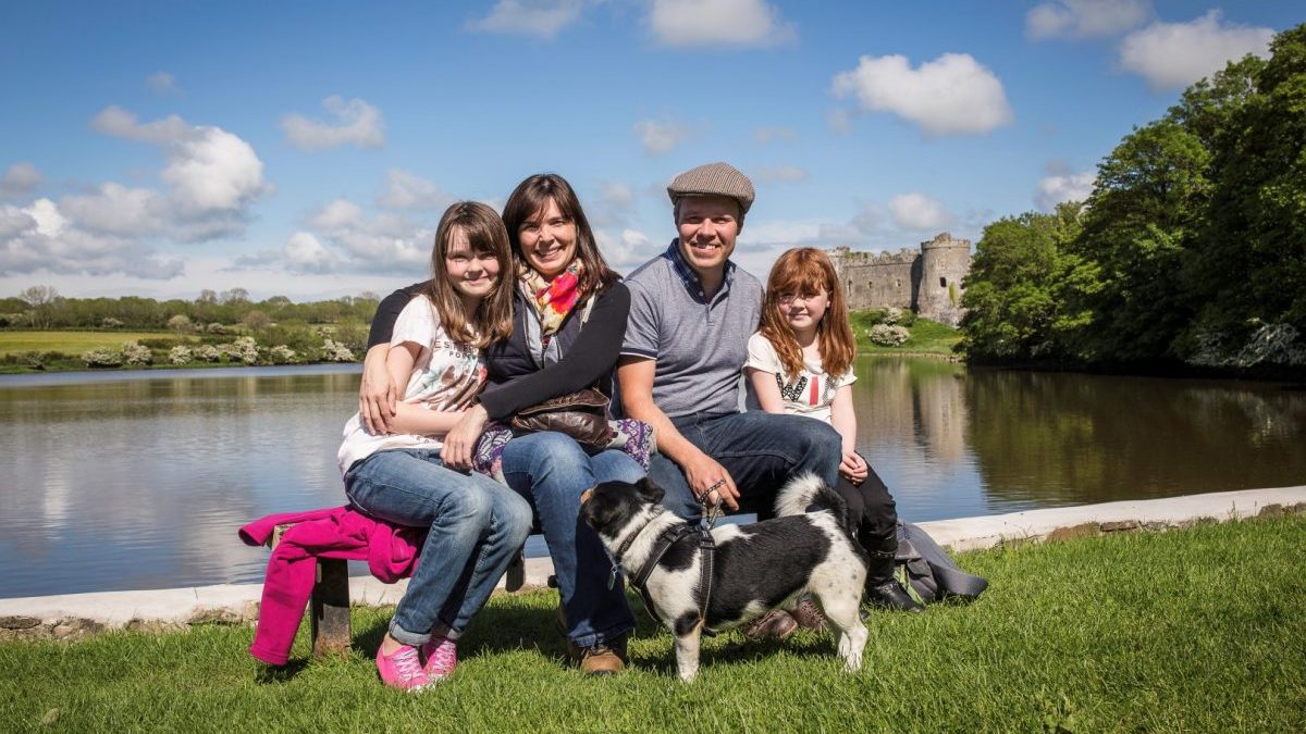 Family of four with dog sitting on Carew millpond with Carew Castle in background