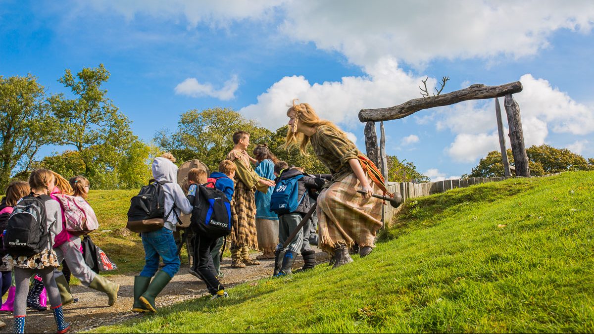 A costumed guide is running up a hill with a group of people