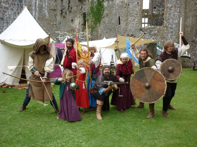 Group of people in medieval dress holding bows, swords and shields