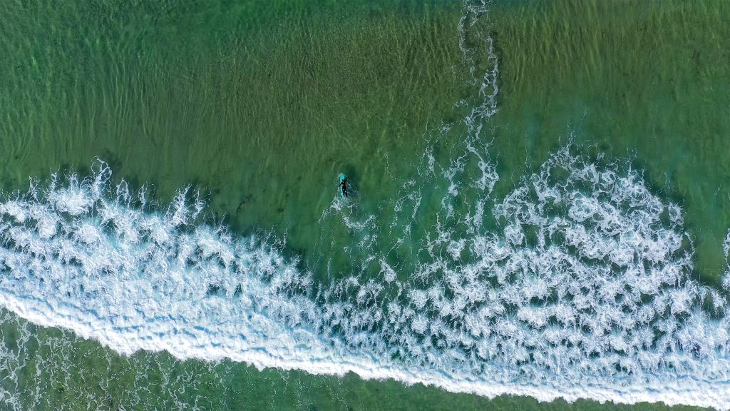 Aerial photograph of a surfer amongst breaking waves