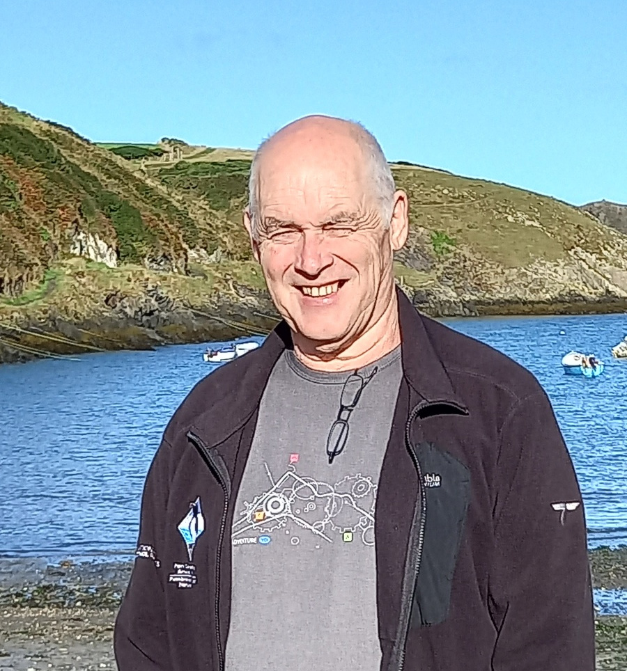 White adult male with grey hair with cliffs and sea in the background