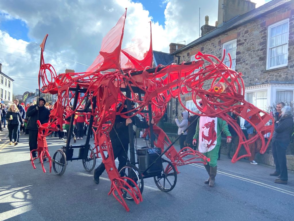 Giant red dragon puppet parading through a street