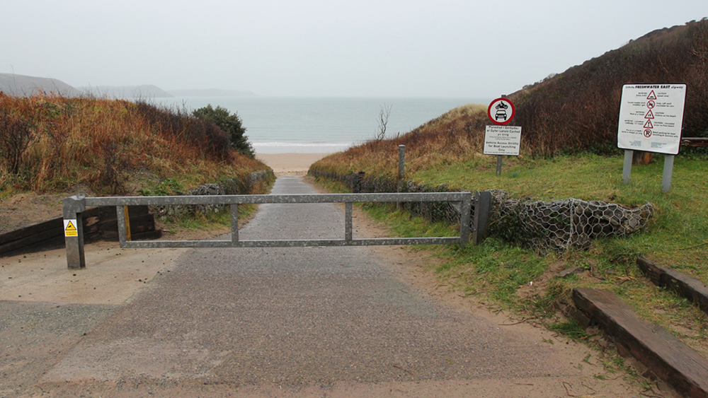 Closed gate across a road leading to a beach