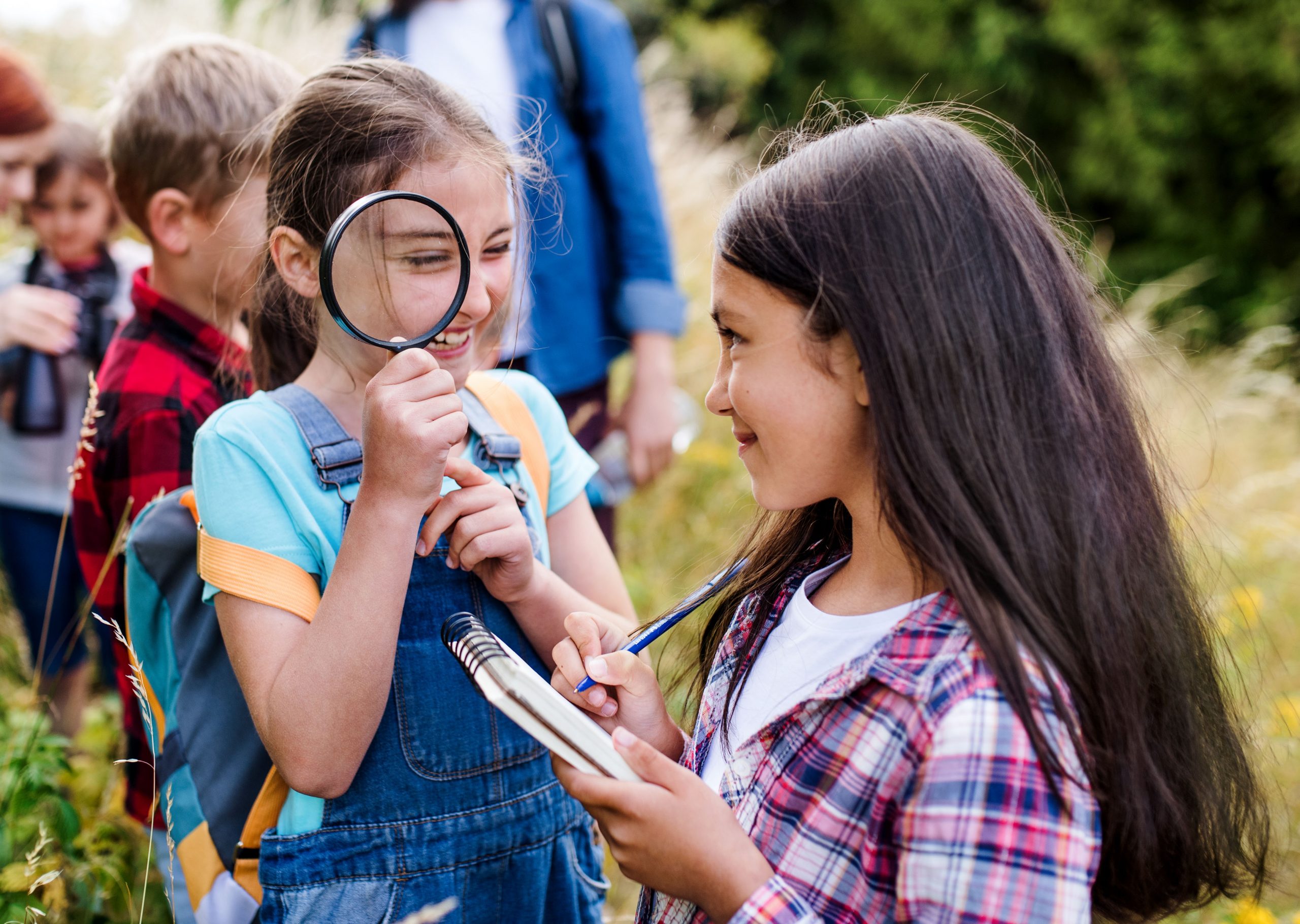 A group of small school children with teacher on field trip in nature, learning science.