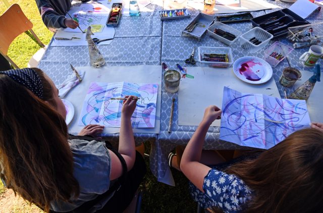 Group of children sitting around a table painting as part of workshop