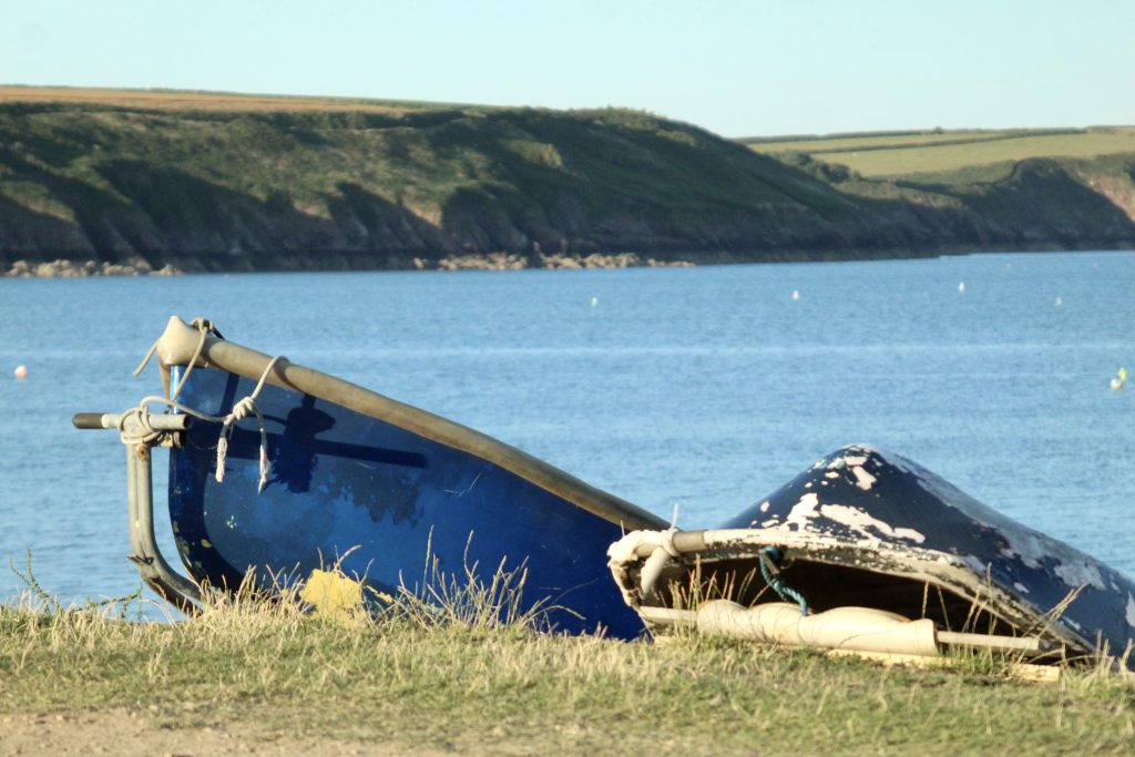 Two boats resting on the shore next to the sea on a sunny day. Location pictured is Dale, Pembrokeshire