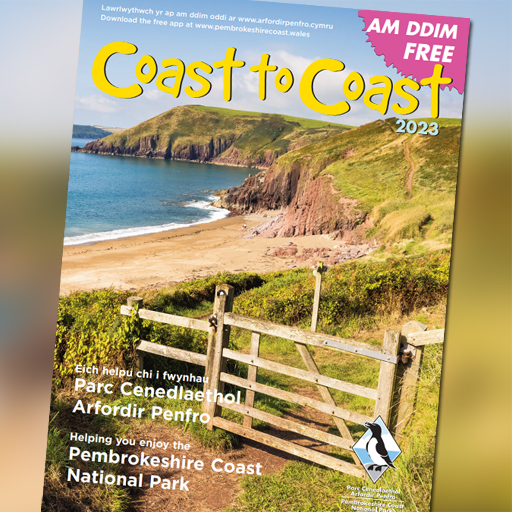 Cover of a magazine titled 'Coast to Coast' which features a coastal scene including a wooden gate across a footpath leading to a sandy beach with red sandstone cliffs in the distance.