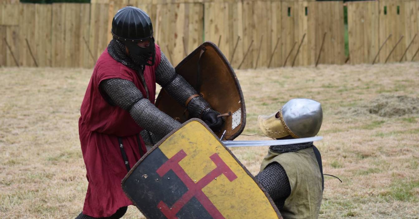Two costumed knights engaged in a sword fight