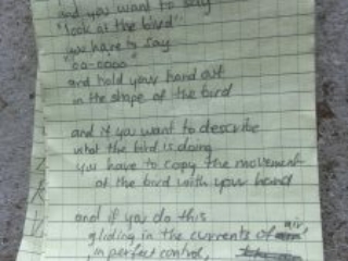 Poem written in a notebook. It reads: If you are playing monkeys and you want to say "look at the bird" you have to say "oo-oooo" and hold your hand out in the shape of the bird  And if you want to describe what the bird is doing You have the bird is doing You have to copy the movement  of the bird with your hand  and if you do this gliding in the current of air In perfect control, tensing, poised ready to dive and every finger, a feather at one with the wind, you can for a moment, become the bird