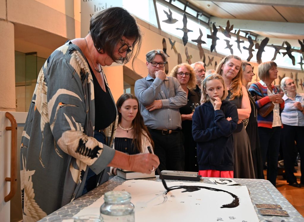 Artist Jackie Morris working in front of a group of curious onlookers