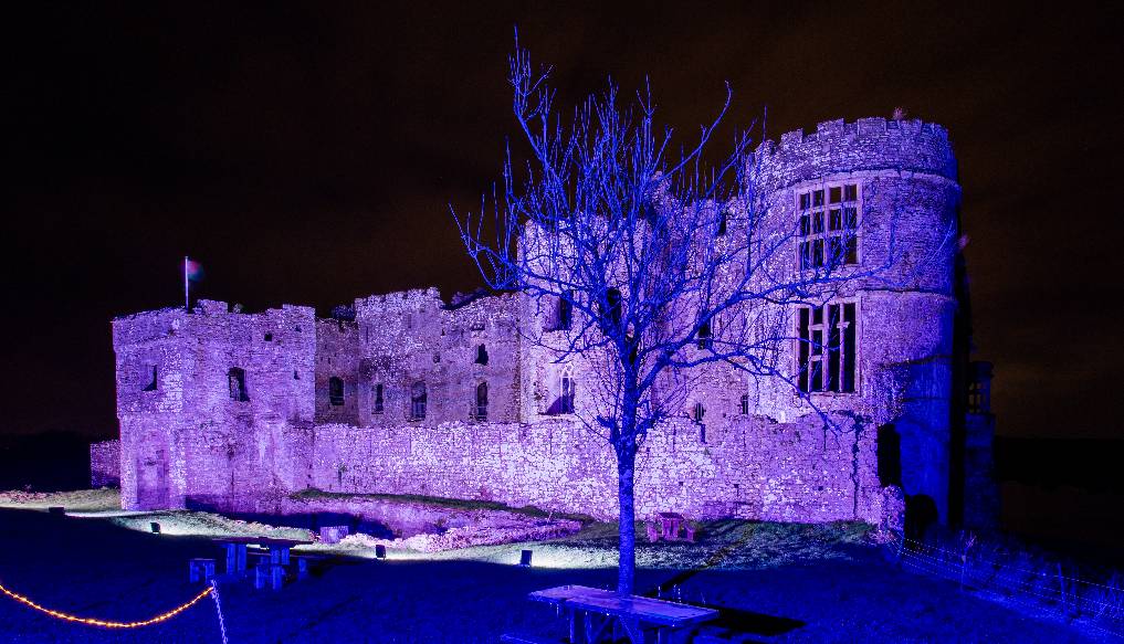 Carew Castle at night lit up in purple