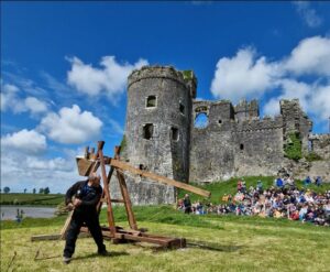 A giant trebuchet being fired in the grounds of Carew Castle