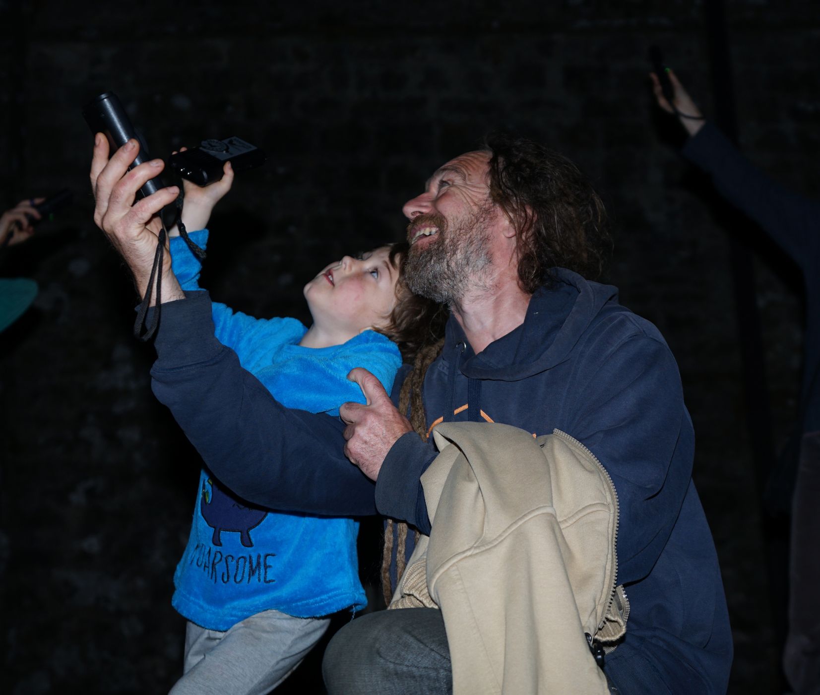 A father and son use a bat detector on a dark night