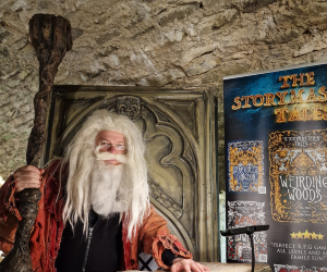 An old man who looks like Santa, sitting on a wooden throne
