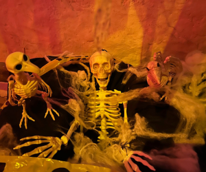 Three skeleton decorations with cobwebs and spooky lighting.
