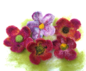 Five felted wool flowers in shades of pink, red, and purple, with yellow and green centers.
