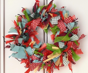 A festive, homemade wreath made from strips of red, green, and white fabric with polka dot and plaid patterns.